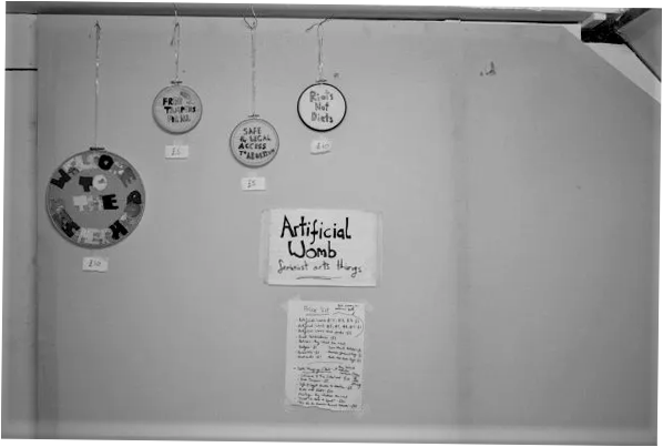 A black and white photograph of embroidery hoops hanging for sale on the wall