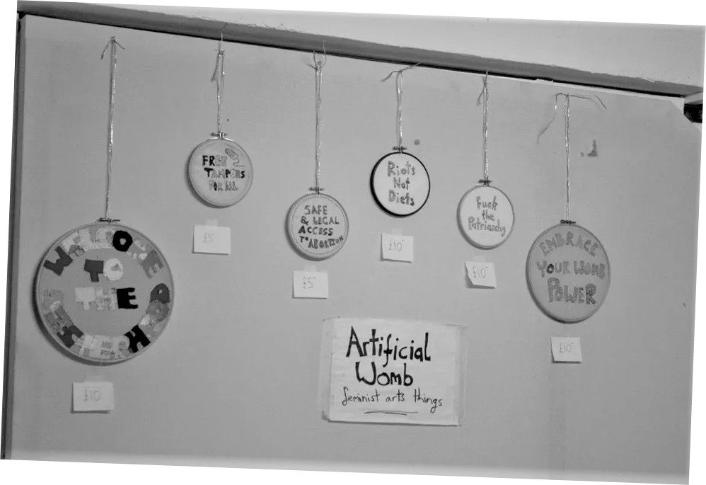 A close up black and white photograph of embroidery hoops hanging for sale on the wall